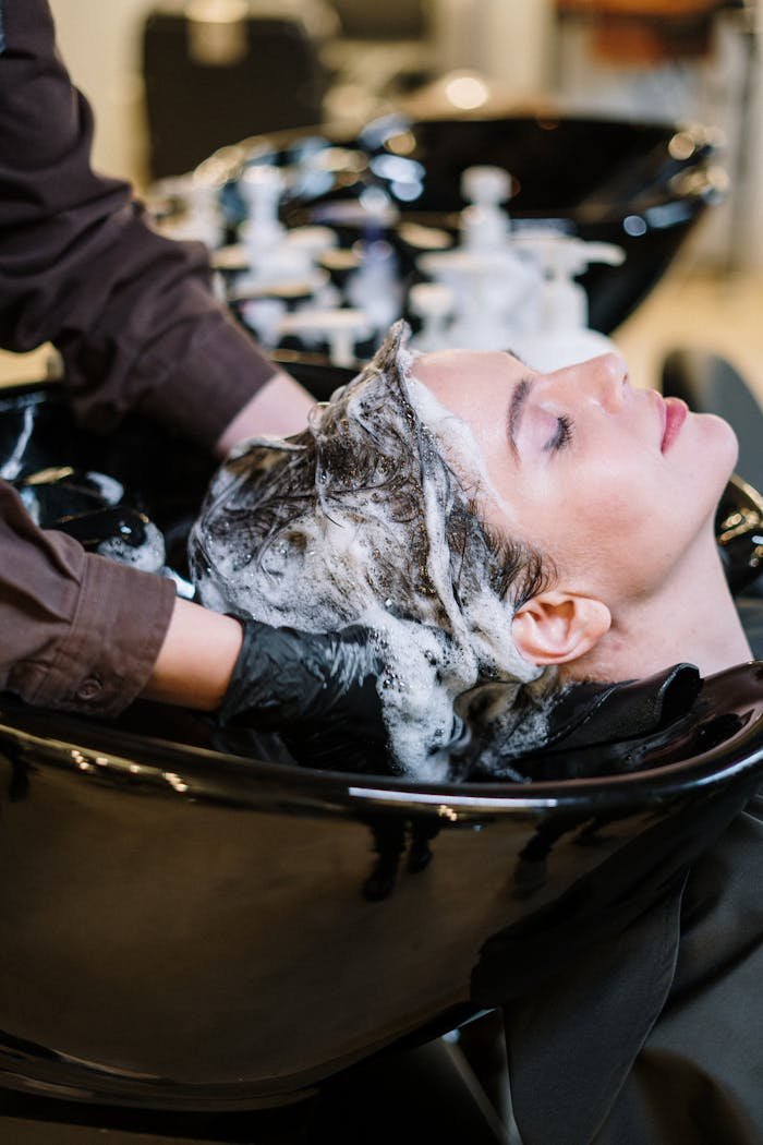 Professional hair stylist washing woman's hair in a modern salon setting.